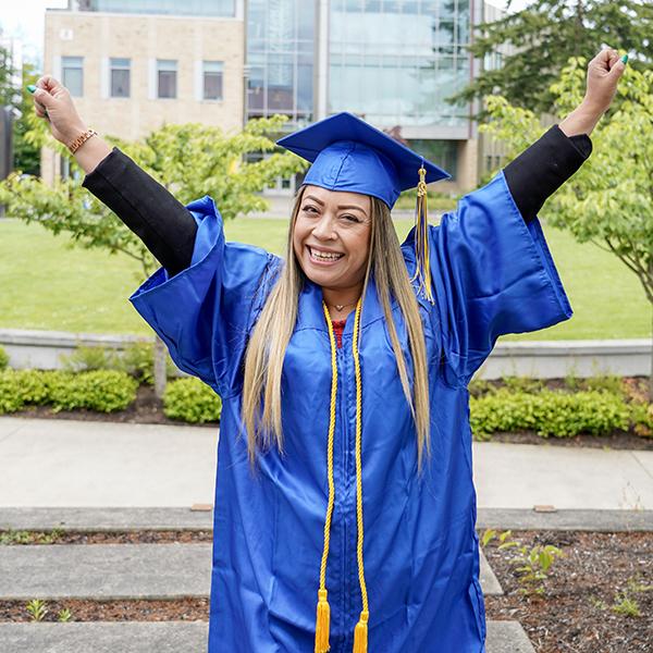 grad with blue regalia arms up